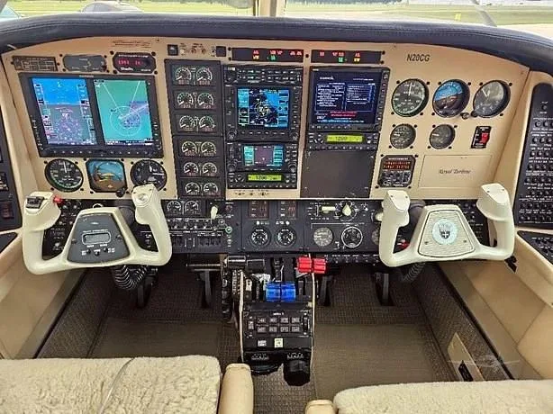 The cockpit of a twin-engine aircraft, featuring a modern avionics suite with multiple display screens and traditional gauges.