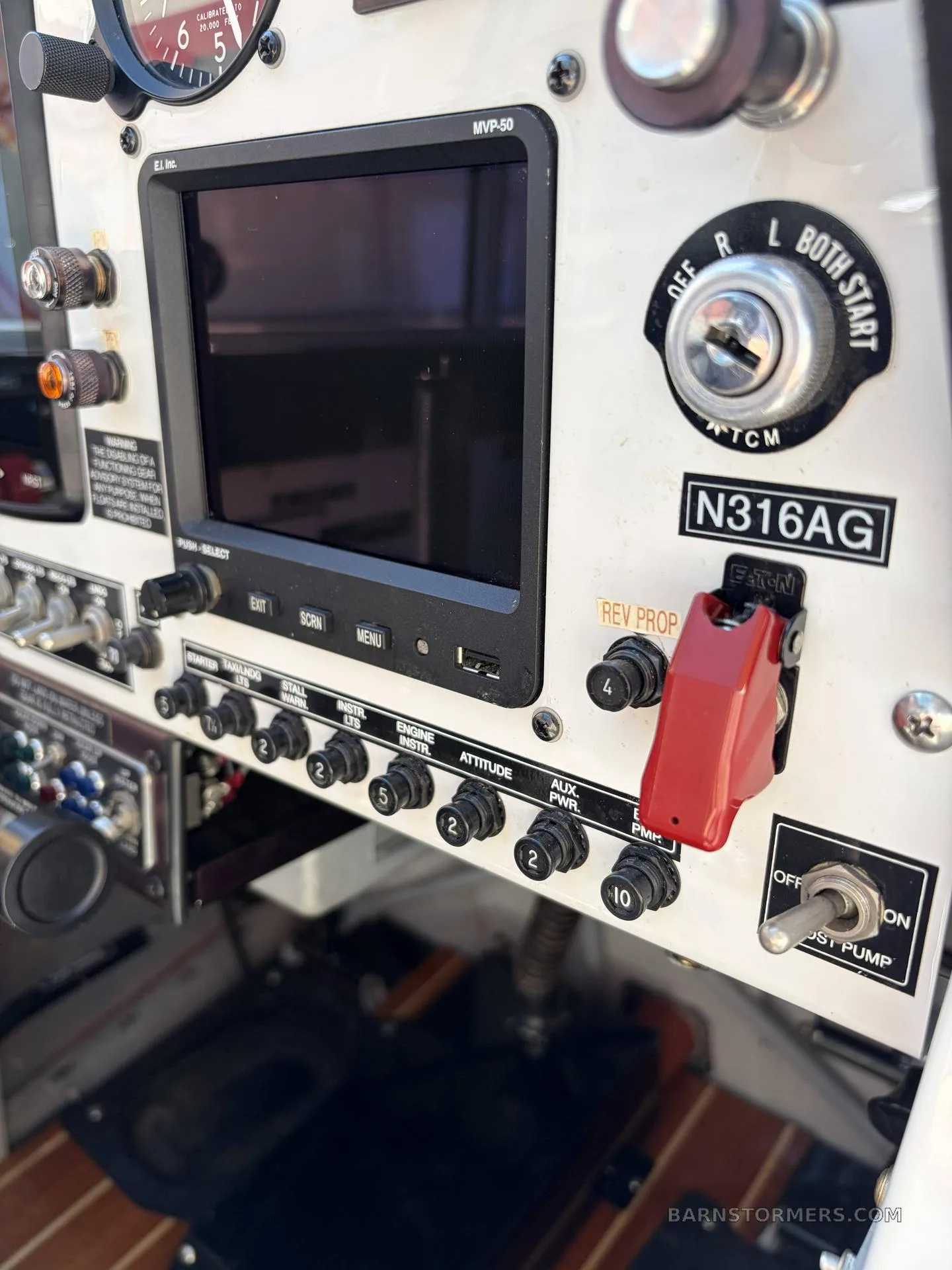 A close-up of the right side of an aircraft's instrument panel, showing a digital display, ignition switch, and various control buttons.