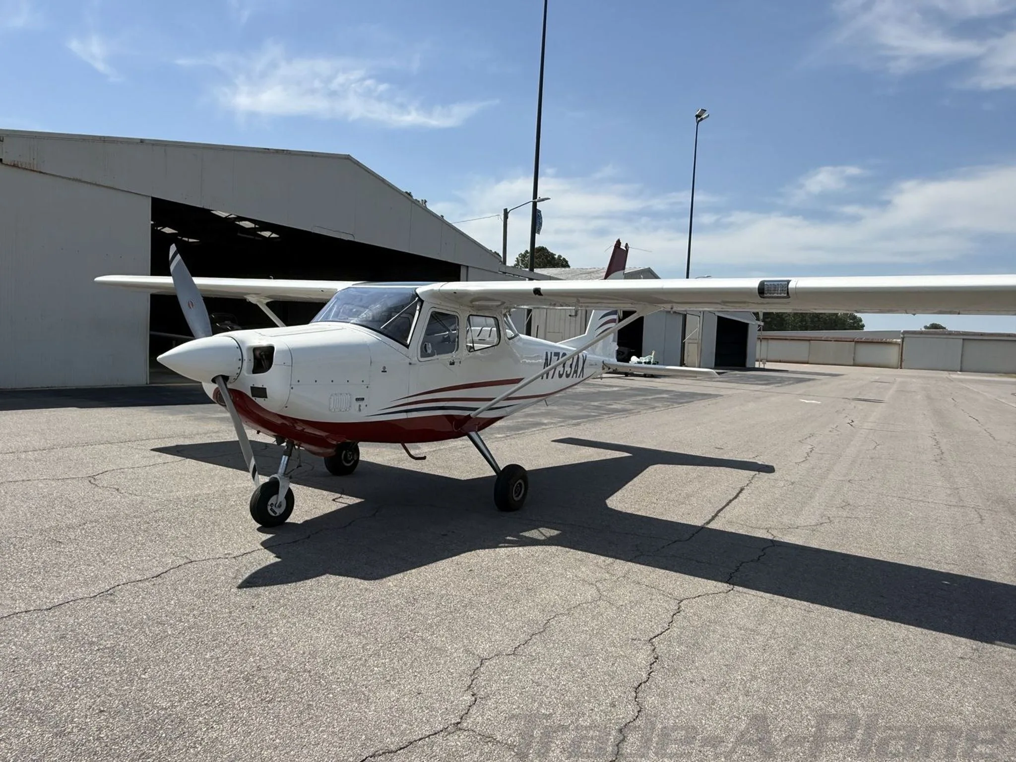 Three-quarter front view of the white and red single-engine aircraft N733AX on an airfield.