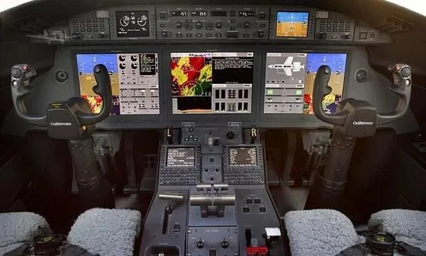 The advanced glass cockpit of a Gulfstream aircraft with multiple display screens and control yokes.