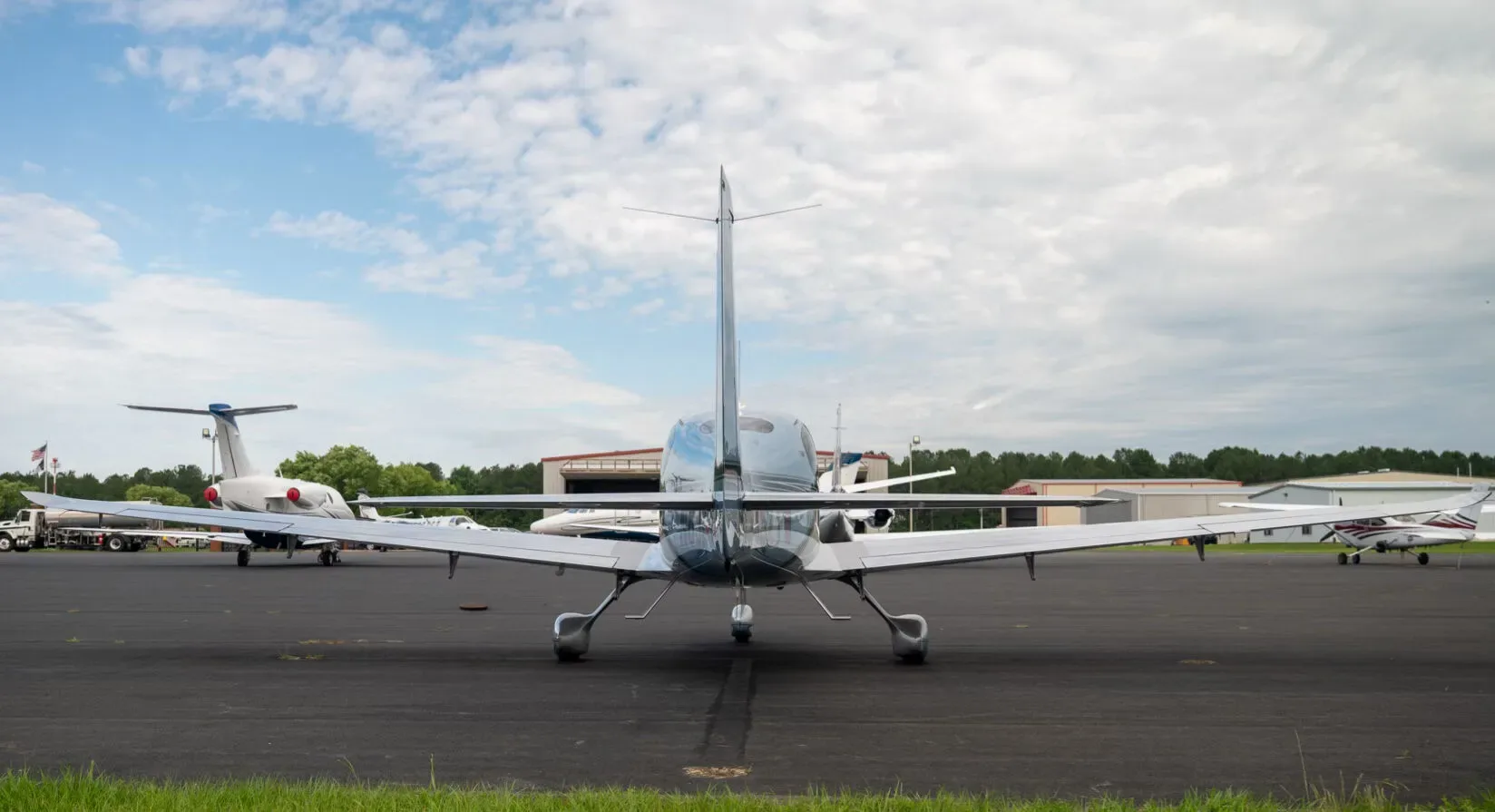 A rear view of a blue and silver Cirrus SR22 aircraft, N852TW, parked on an airport tarmac with other planes.