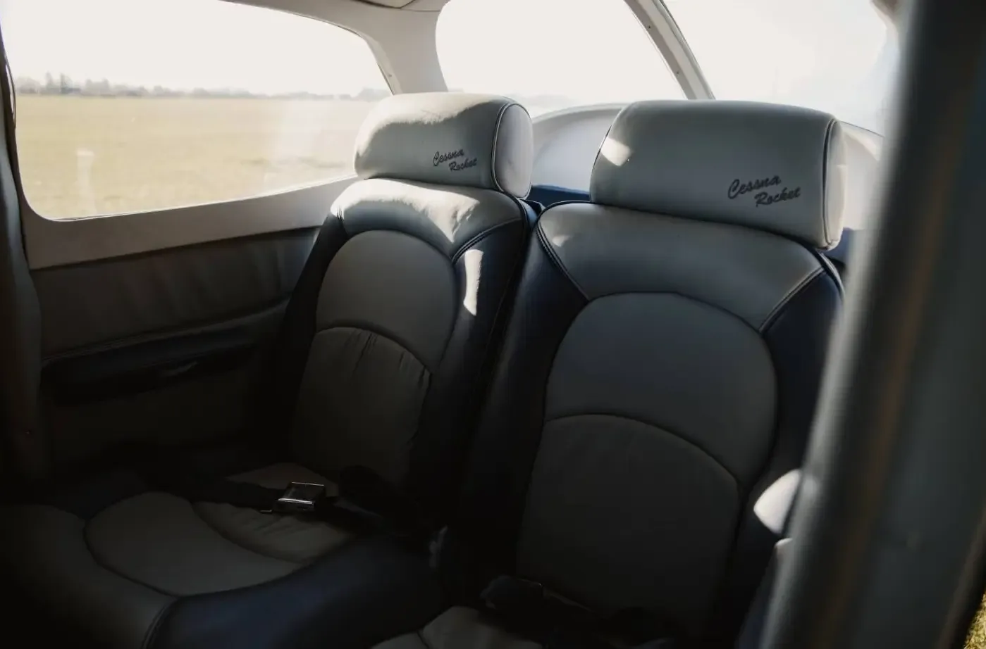 The grey and black leather rear passenger seats of a Cessna aircraft, with "Cessna Rocket" embroidered on the headrests.