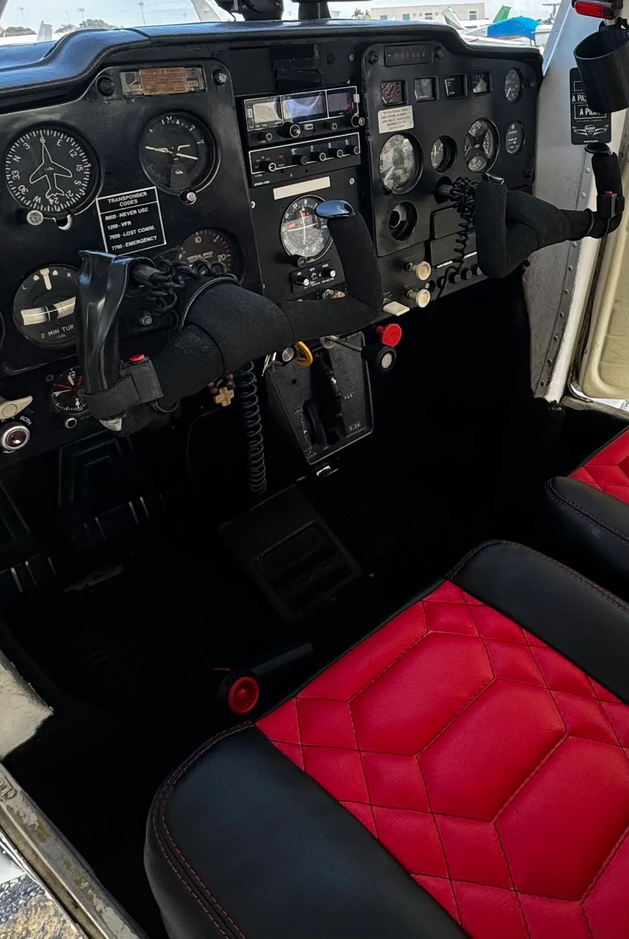 Close-up view of the instrument panel and controls of a Cessna 172, N3640J, with red and black quilted seats visible.