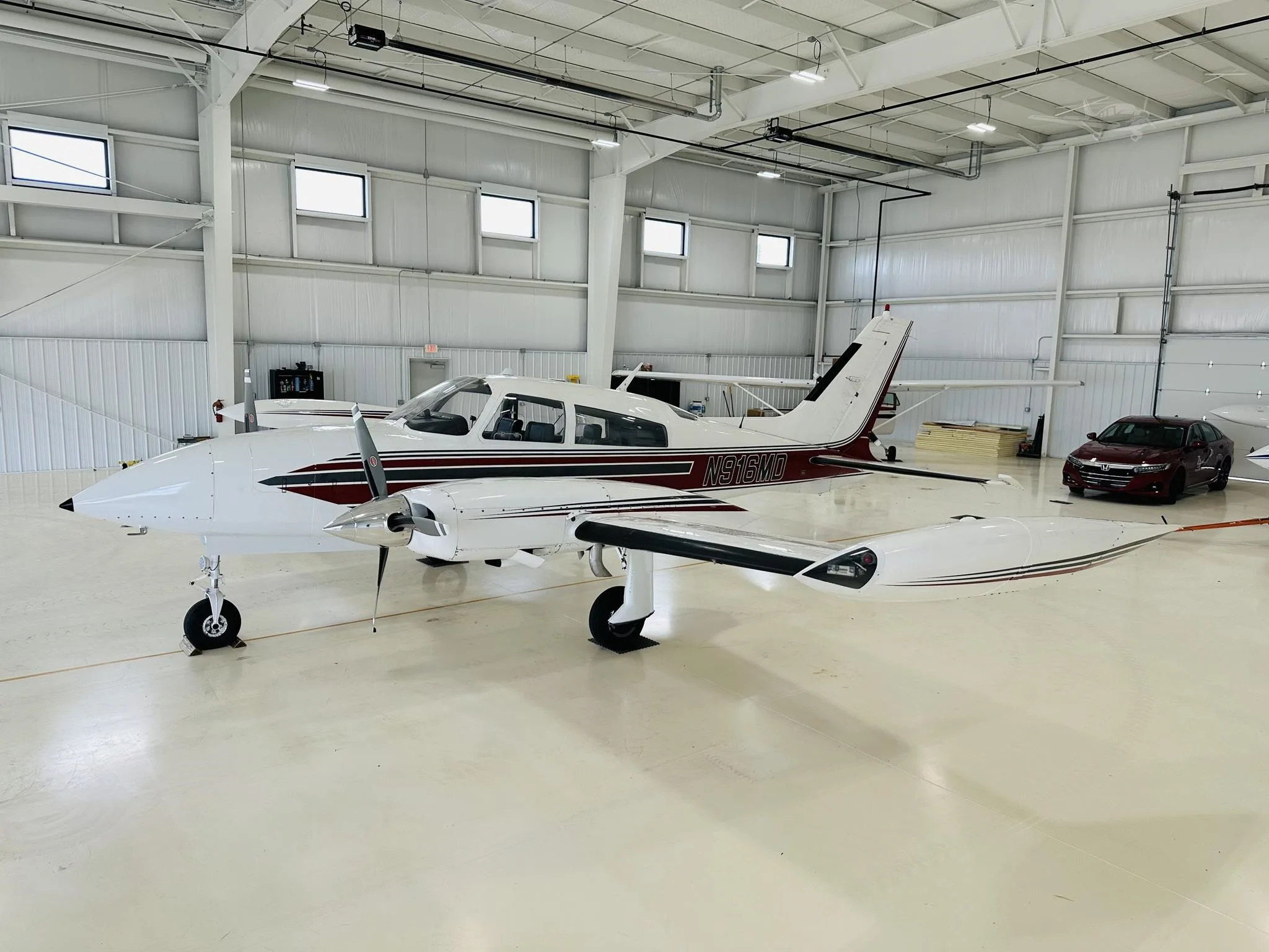 A white and maroon twin-engine propeller aircraft, registration N961D, is parked inside a brightly lit hangar.