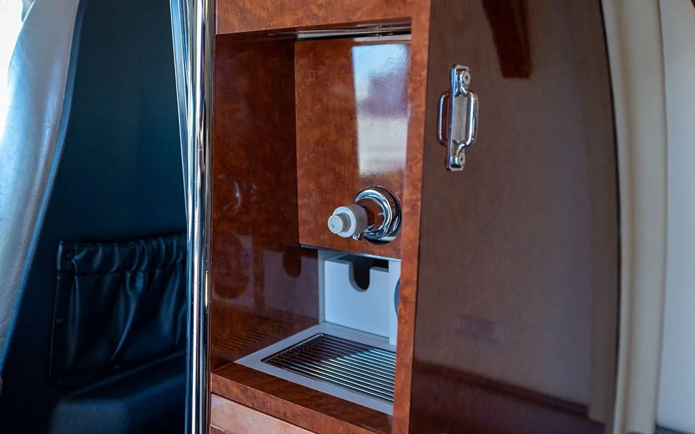 A close-up of a wood-paneled refreshment station with a faucet and sink in the aircraft's interior.