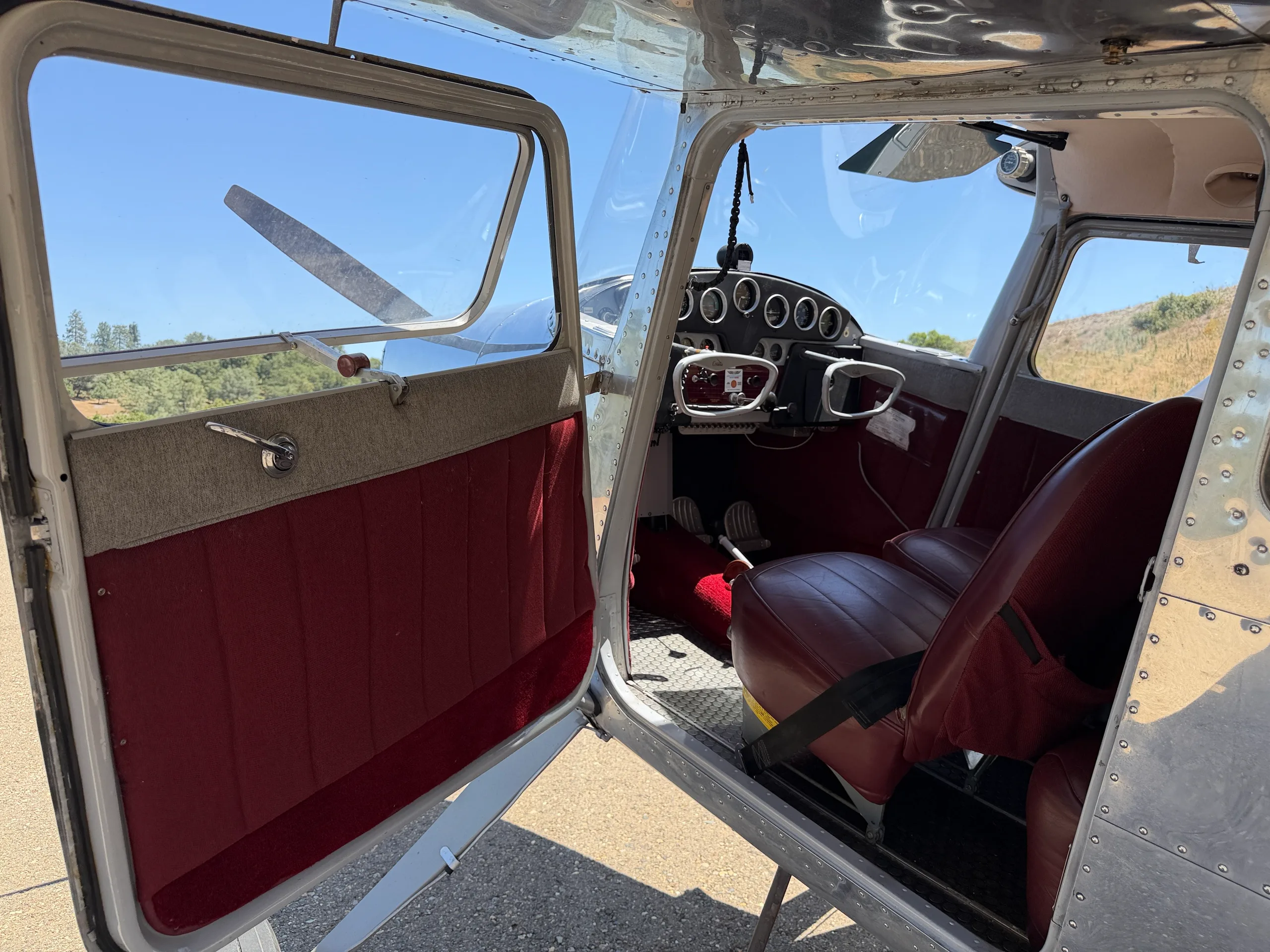 View of the aircraft's open door and the red interior cabin with the cockpit visible.
