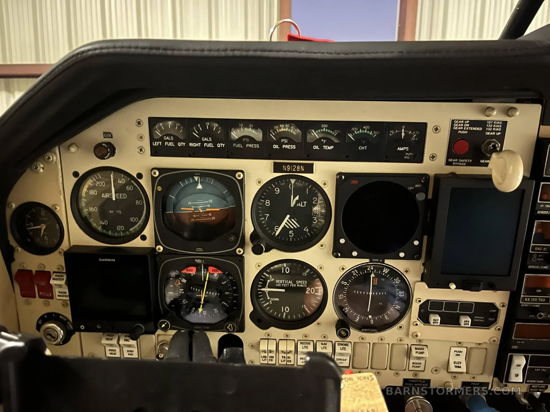 A close-up view of an aircraft cockpit instrument panel with various gauges and avionics, including registration N9128N.