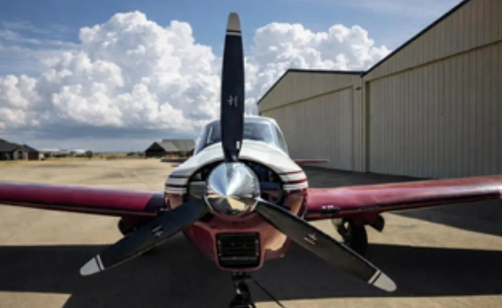 A close-up front view of the propeller and nose of the red and white Bellanca Viking 300.