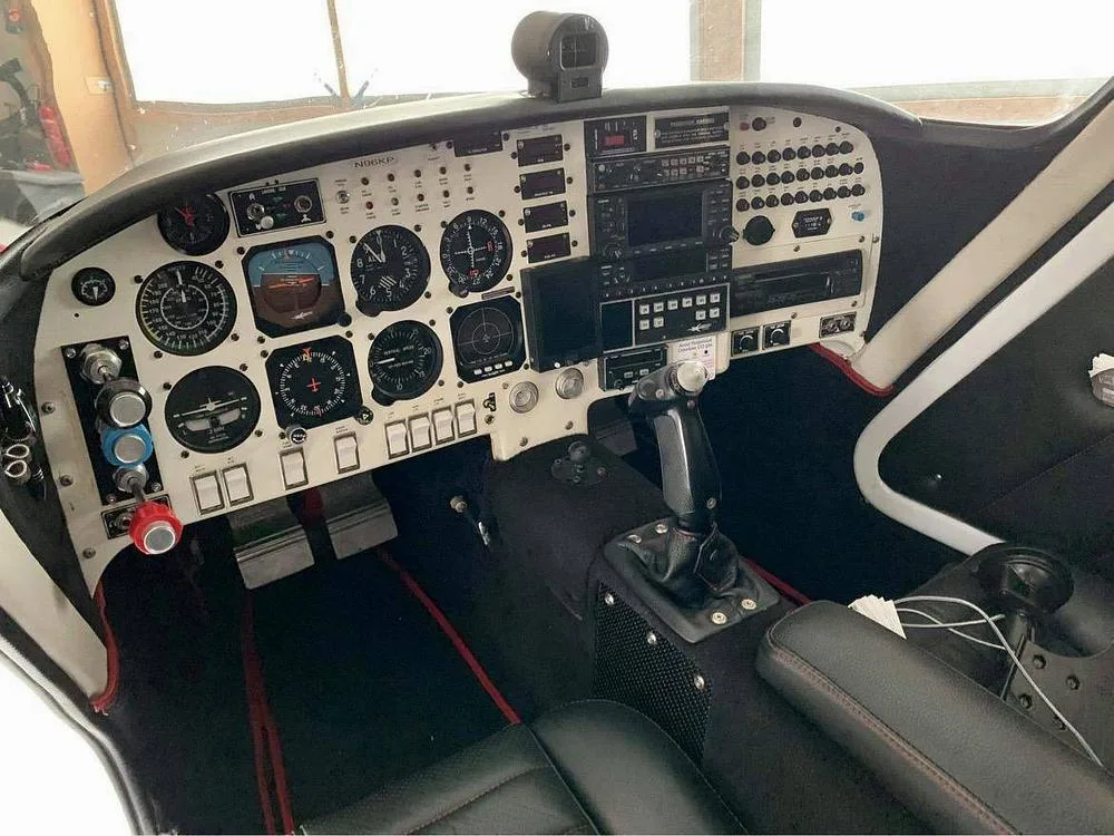 The cockpit of a Velocity aircraft, showing the instrument panel, controls, and black leather seats.