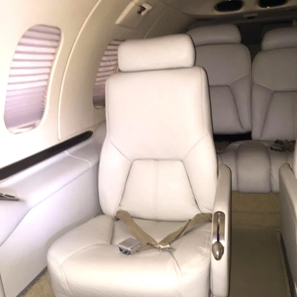 A close-up view of a single light-colored leather seat in an aircraft cabin.