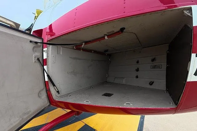 The open cargo compartment of the red and white helicopter, revealing an empty storage space.