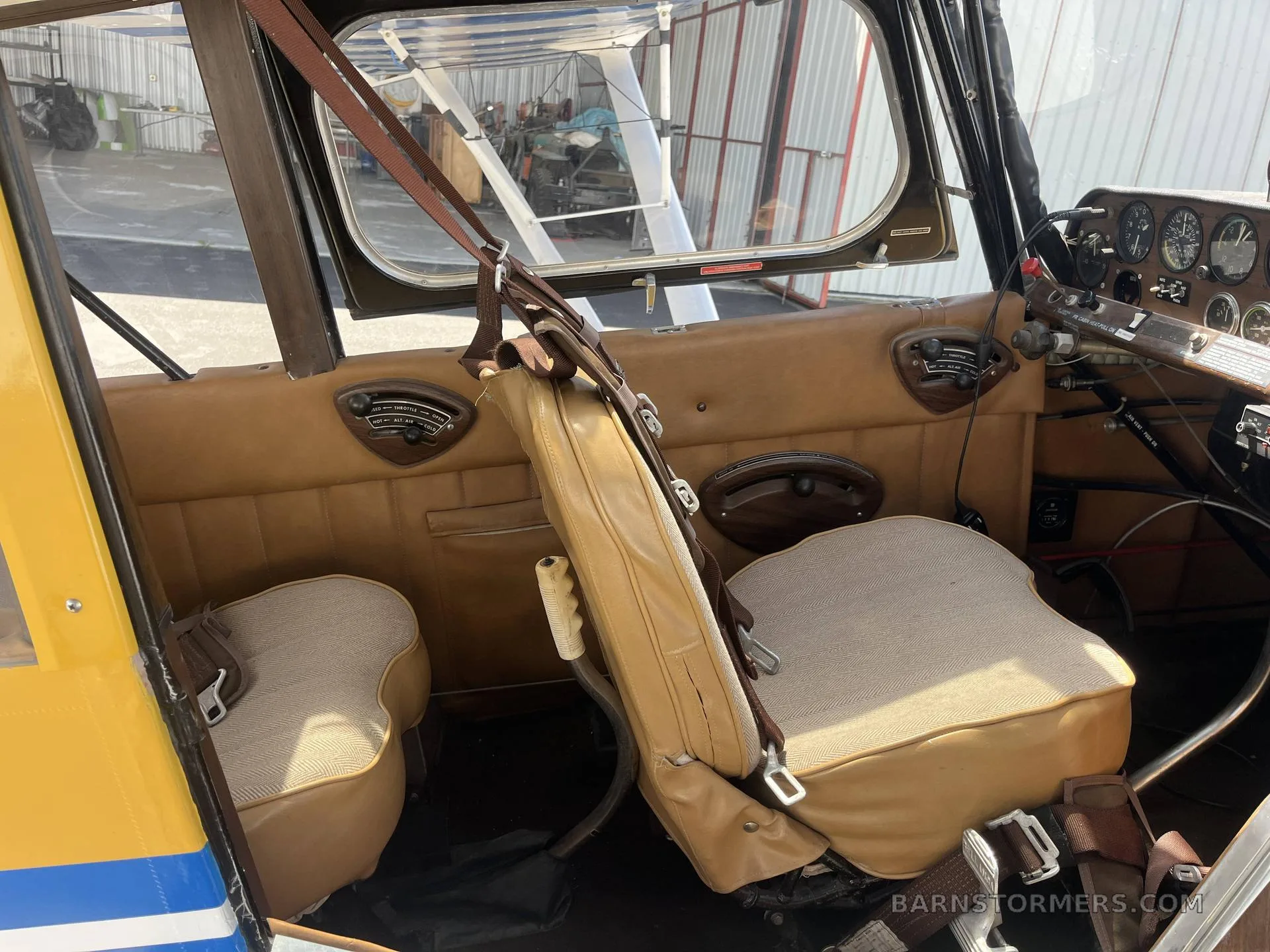 Interior view of an aircraft cabin with brown upholstered seats, brown side panels, and a partial view of the instrument panel.