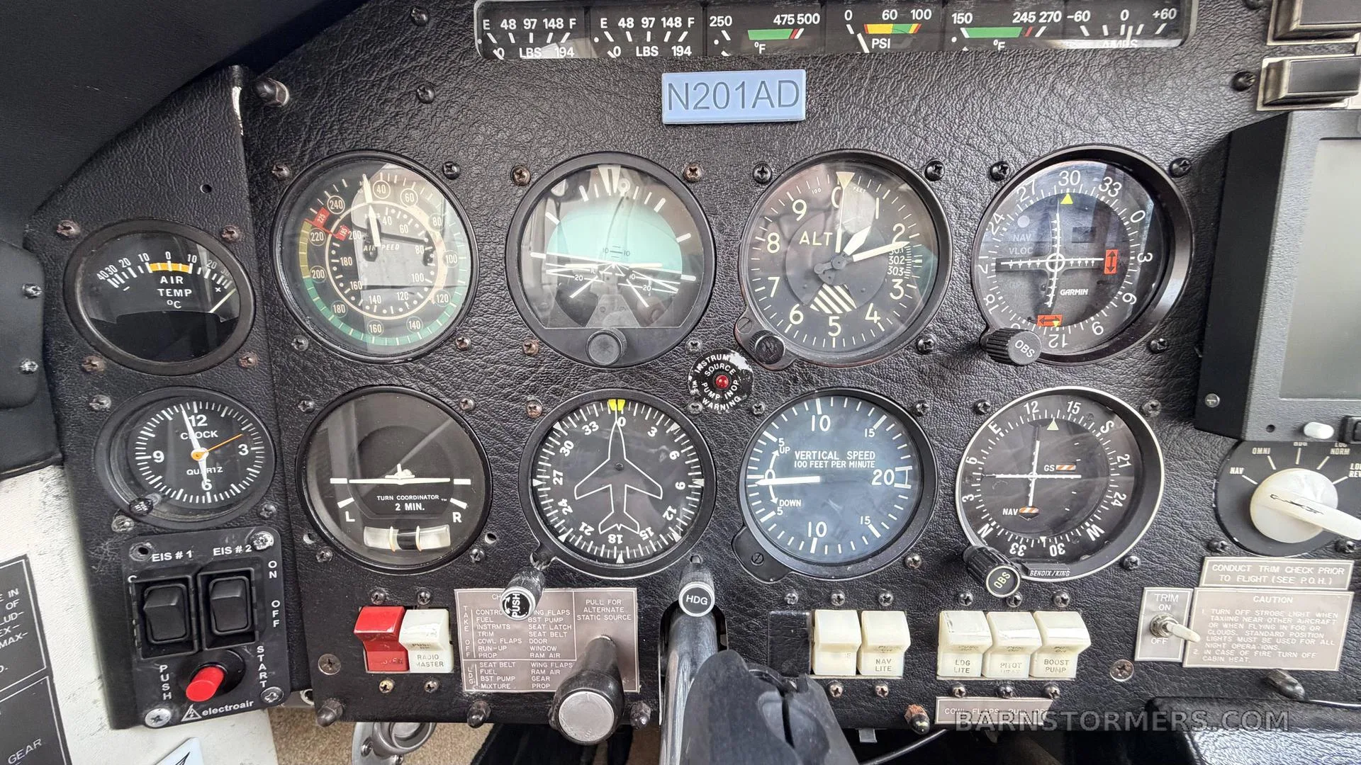 A close-up of an aircraft's instrument panel, featuring various analog gauges and controls, with registration N201AD.