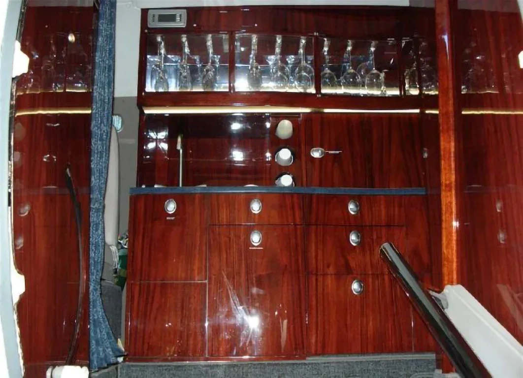 A luxurious aircraft galley with dark polished wood cabinetry and glass holders.