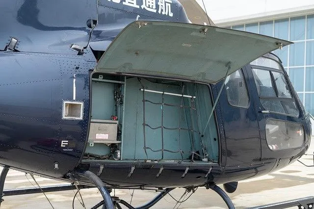 A close-up view of the dark blue helicopter's side, showing an open cargo compartment with a net inside.
