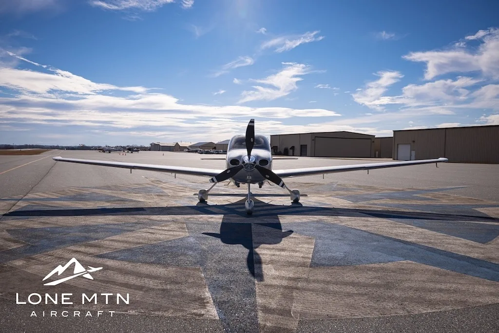 A silver Cirrus SR22T aircraft, N617JJ, parked head-on on an airfield with hangars in the background.