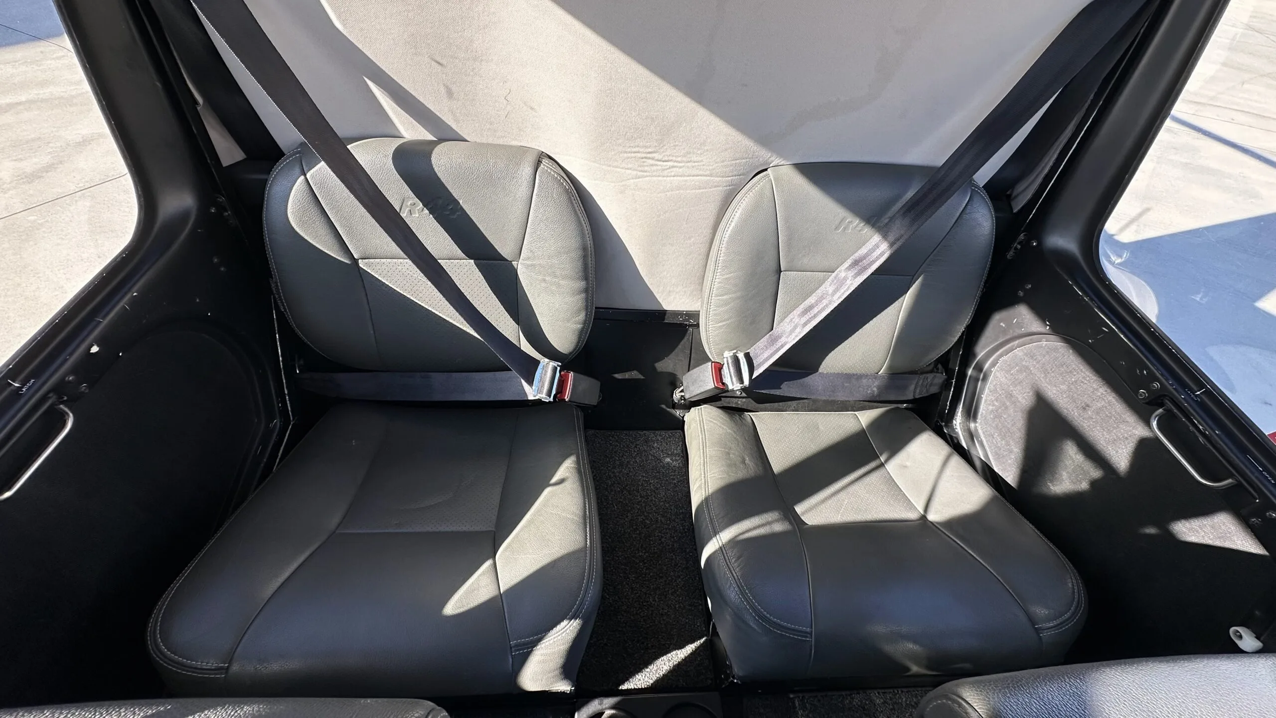 The two grey leather seats in the cabin of a Robinson R44 helicopter.