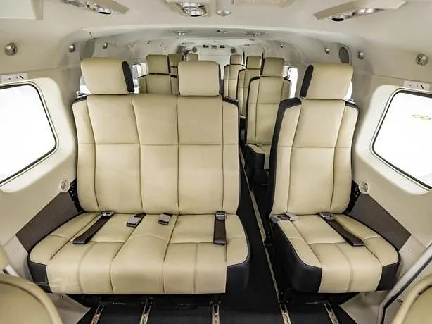The interior cabin of an aircraft features multiple rows of light beige and black passenger seats.