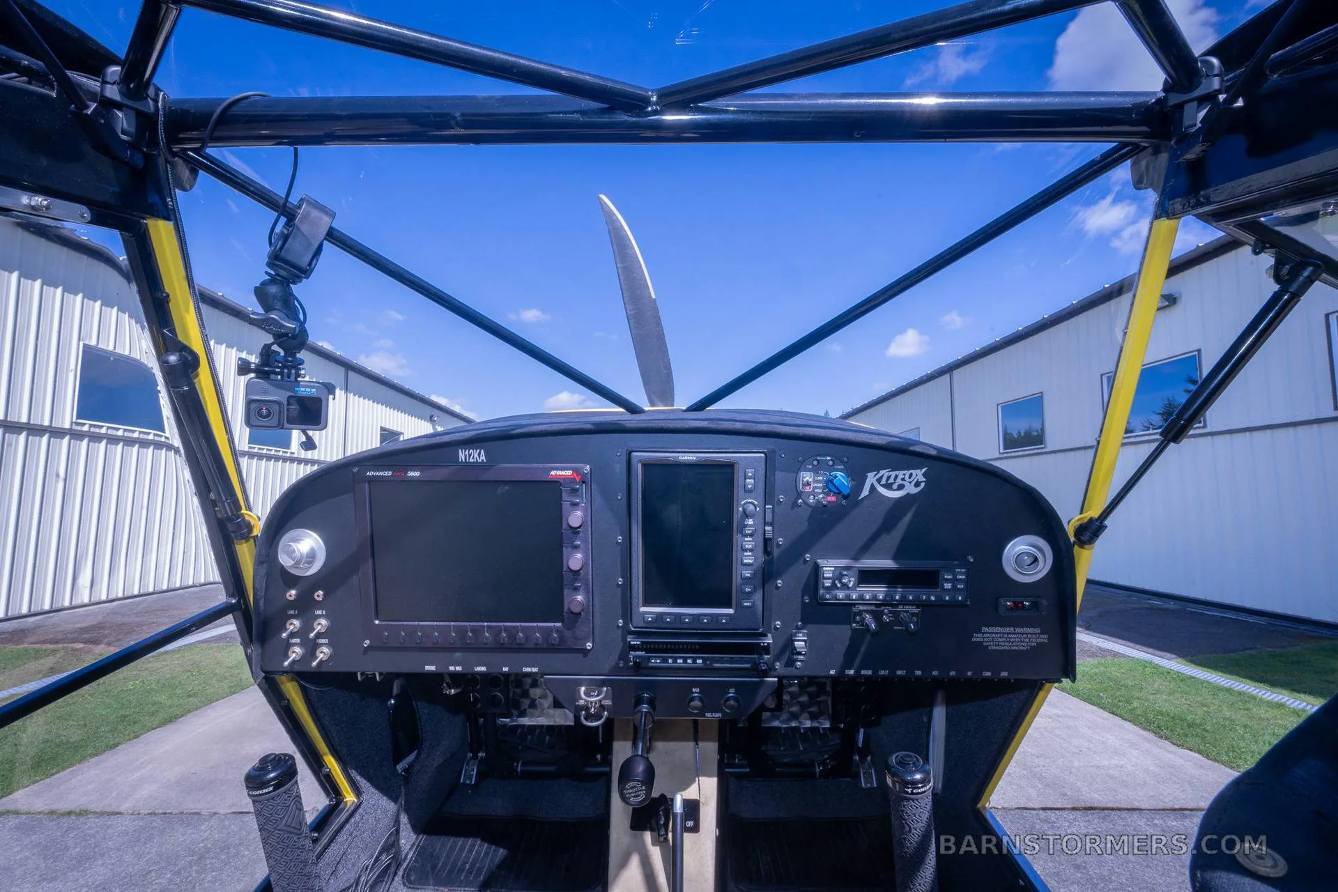 The cockpit of a yellow Kitfox aircraft, showing the instrument panel with digital displays and controls.