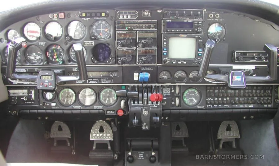 The aircraft's cockpit instrument panel with various analog gauges, avionics, and control yokes.