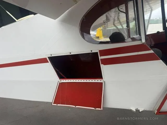 A close-up of the white and red Super Cub fuselage showing an open cargo door on the side.