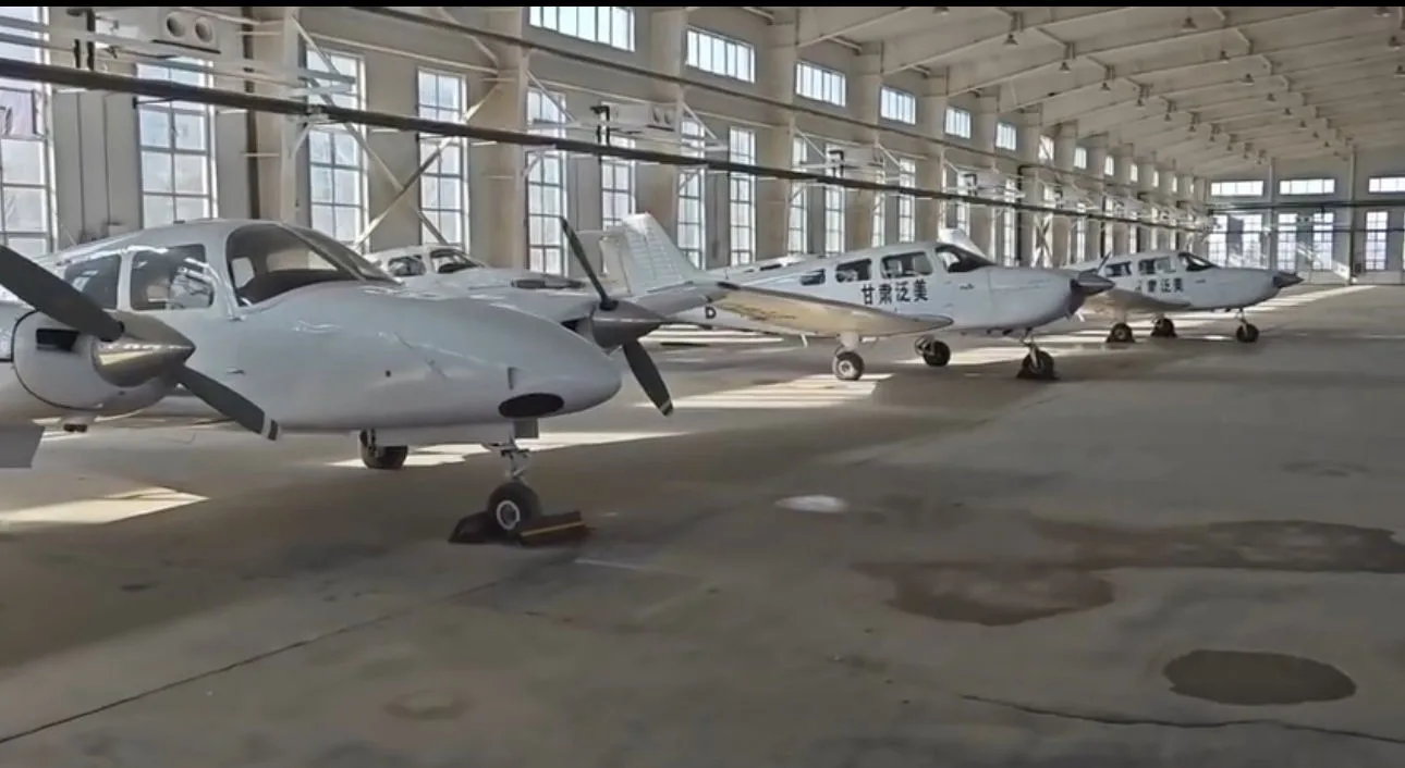 Several white single-engine and twin-engine aircraft parked in a hangar.