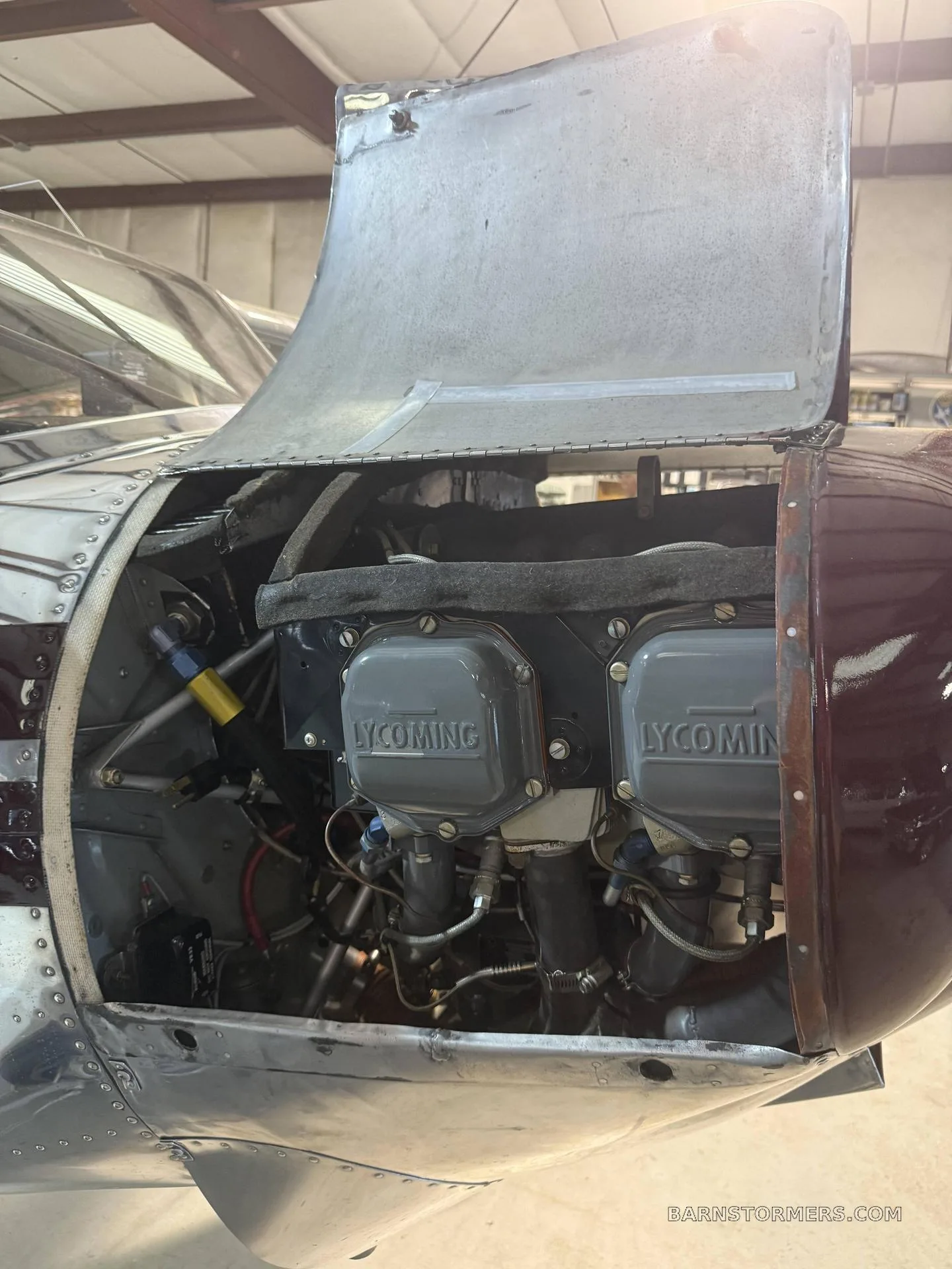 A close-up view of a Lycoming aircraft engine with its cowling open, showing the cylinders and internal components.