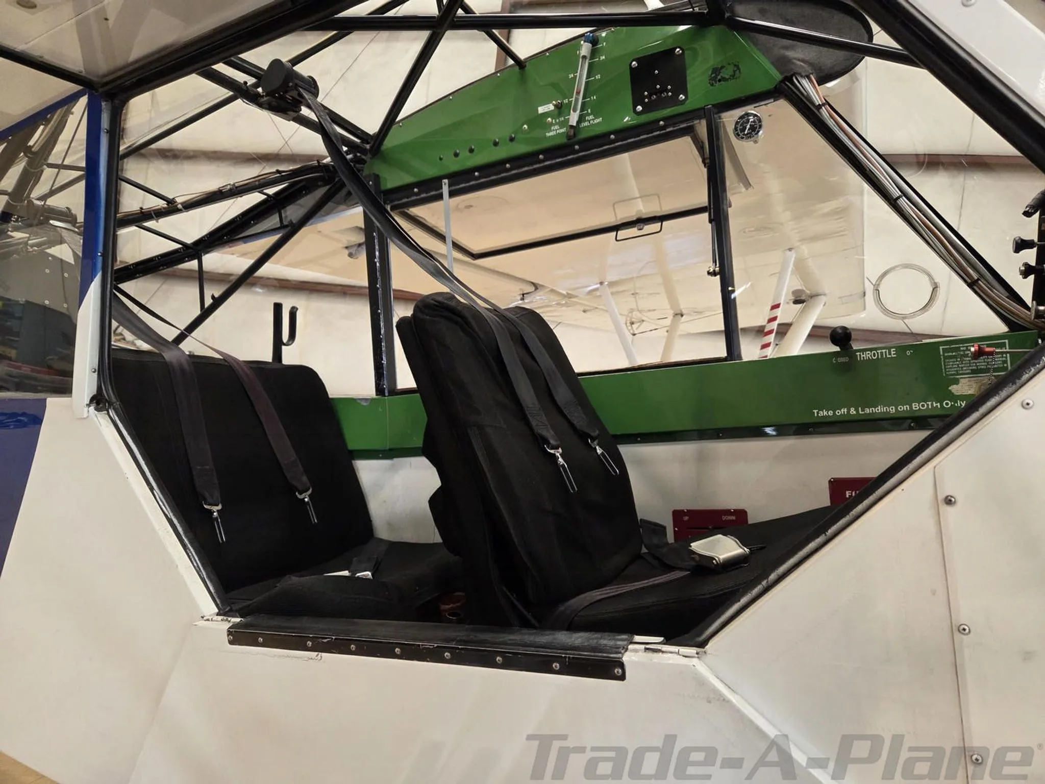 Interior view of the Piper Super Cub cabin showing two black seats and the green overhead panel.