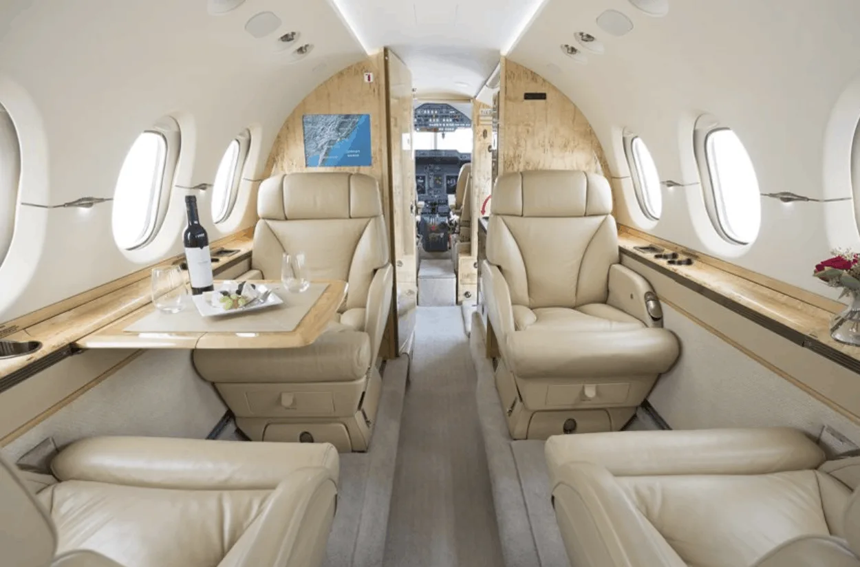 Hawker 400XP cabin interior with leather seats and wood trim.