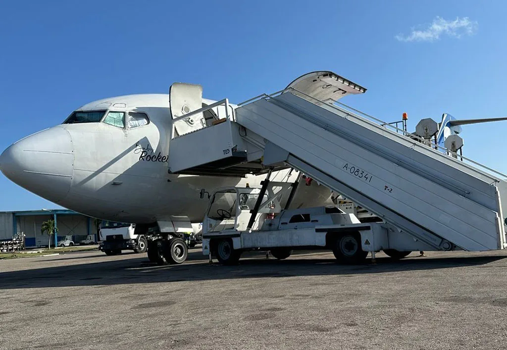 The front section of a UniWorld Air Cargo Boeing 727-200F with mobile stairs attached.