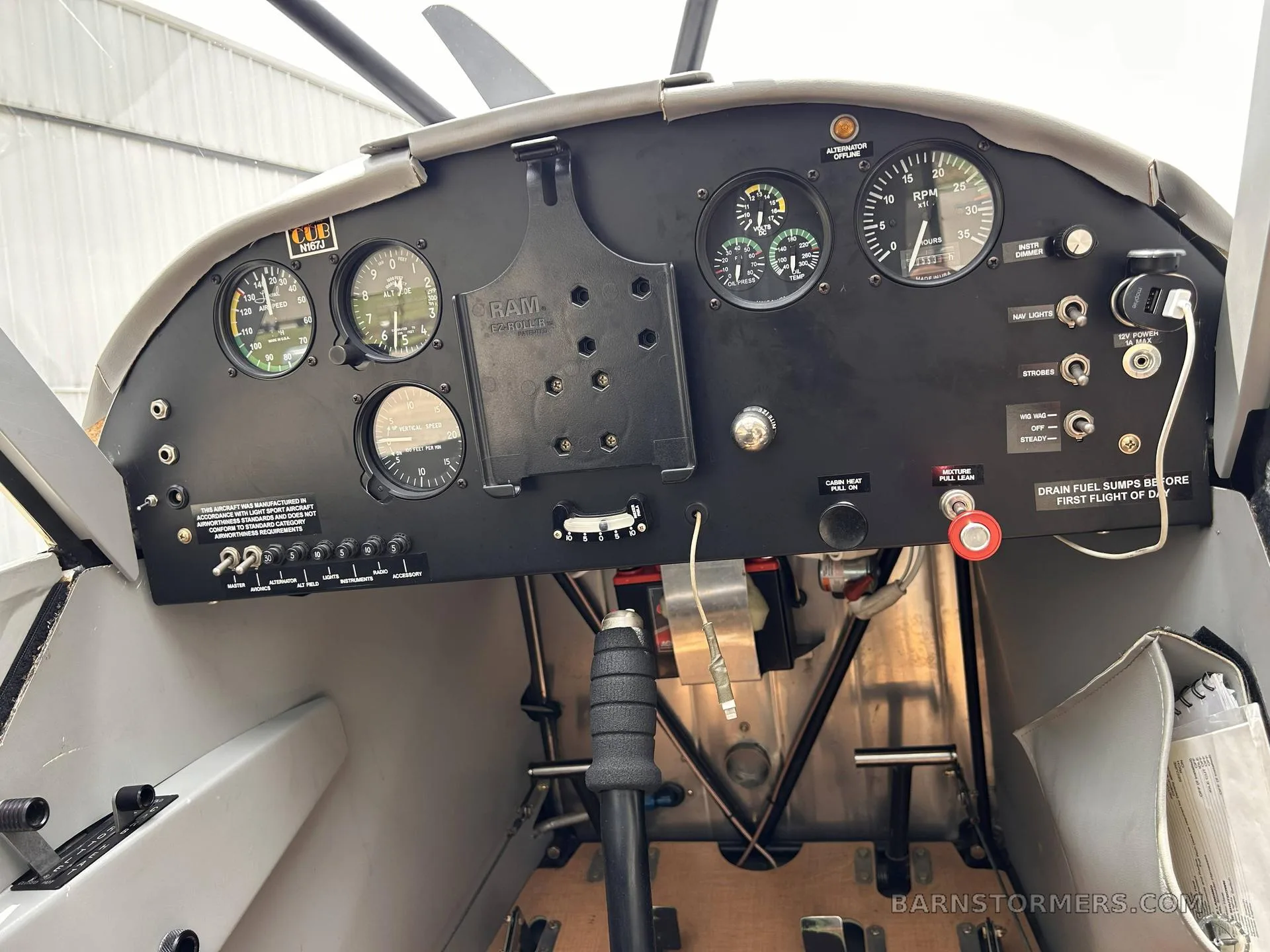 A close-up view of the aircraft's black instrument panel with various gauges, switches, and a control stick.