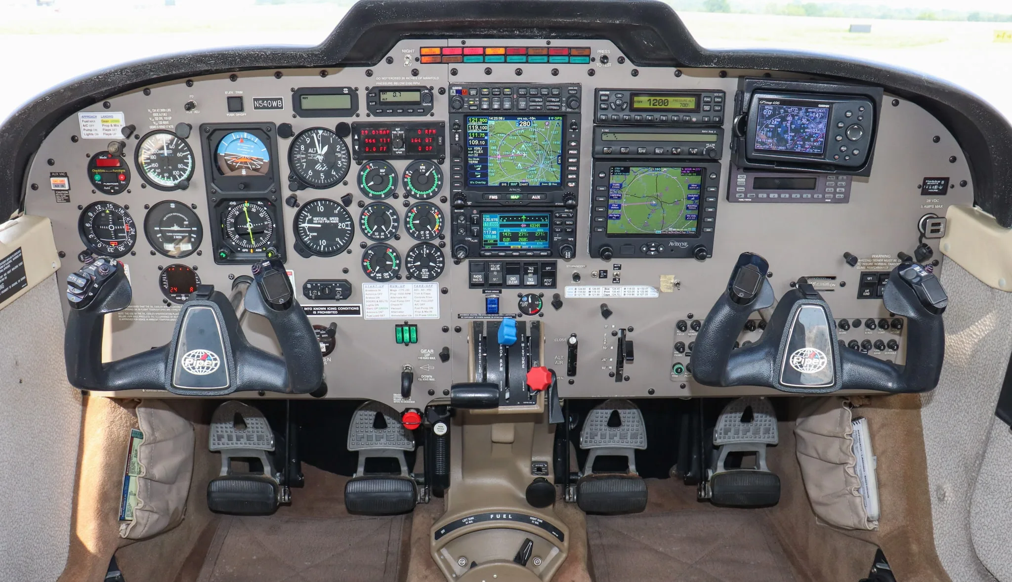 A detailed view of the cockpit of a Piper Saratoga II TC, showing the instrument panel, yokes, and avionics.