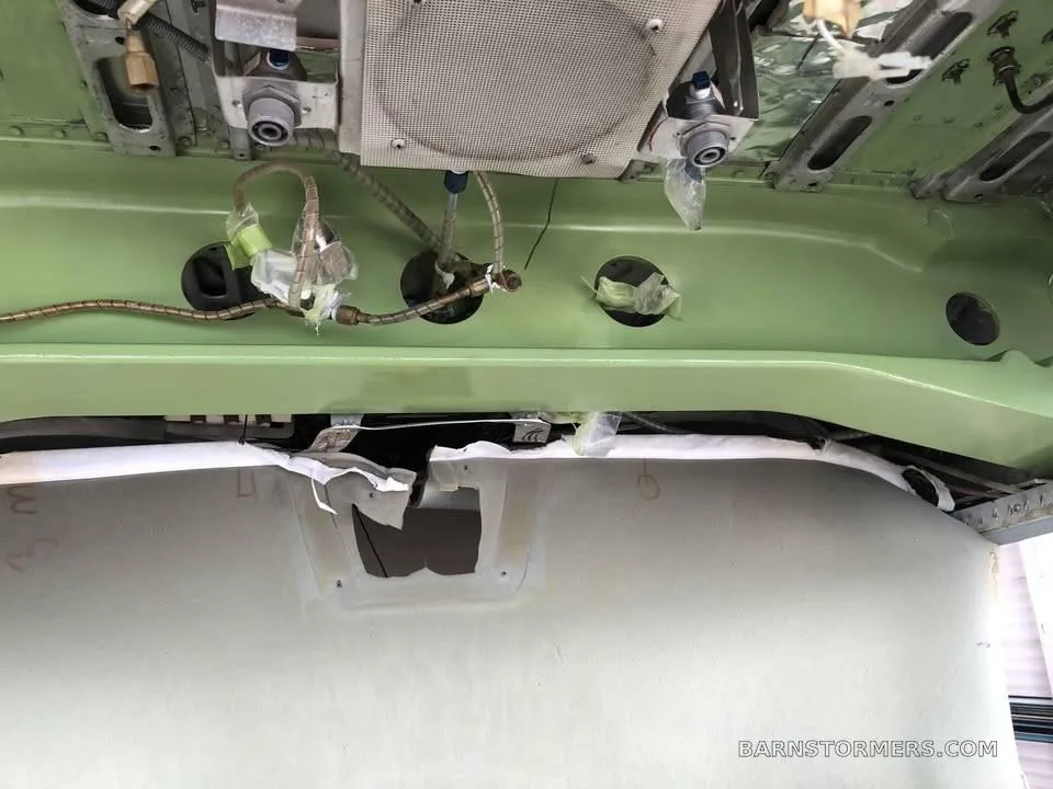 An overhead view of the internal structure of an aircraft, showing wiring, insulation, and green painted ribs.