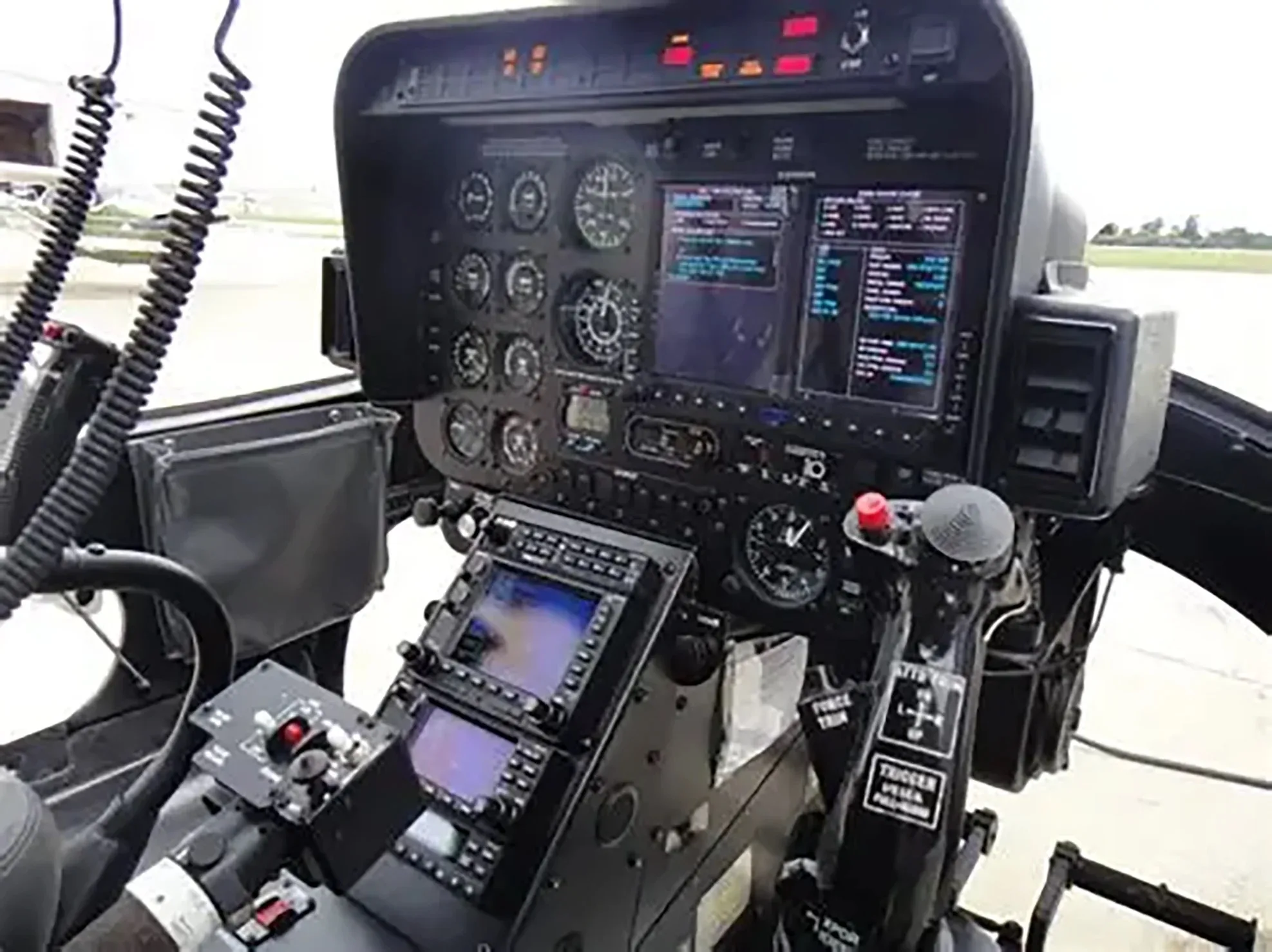 The cockpit of a helicopter showing the instrument panel and flight controls.