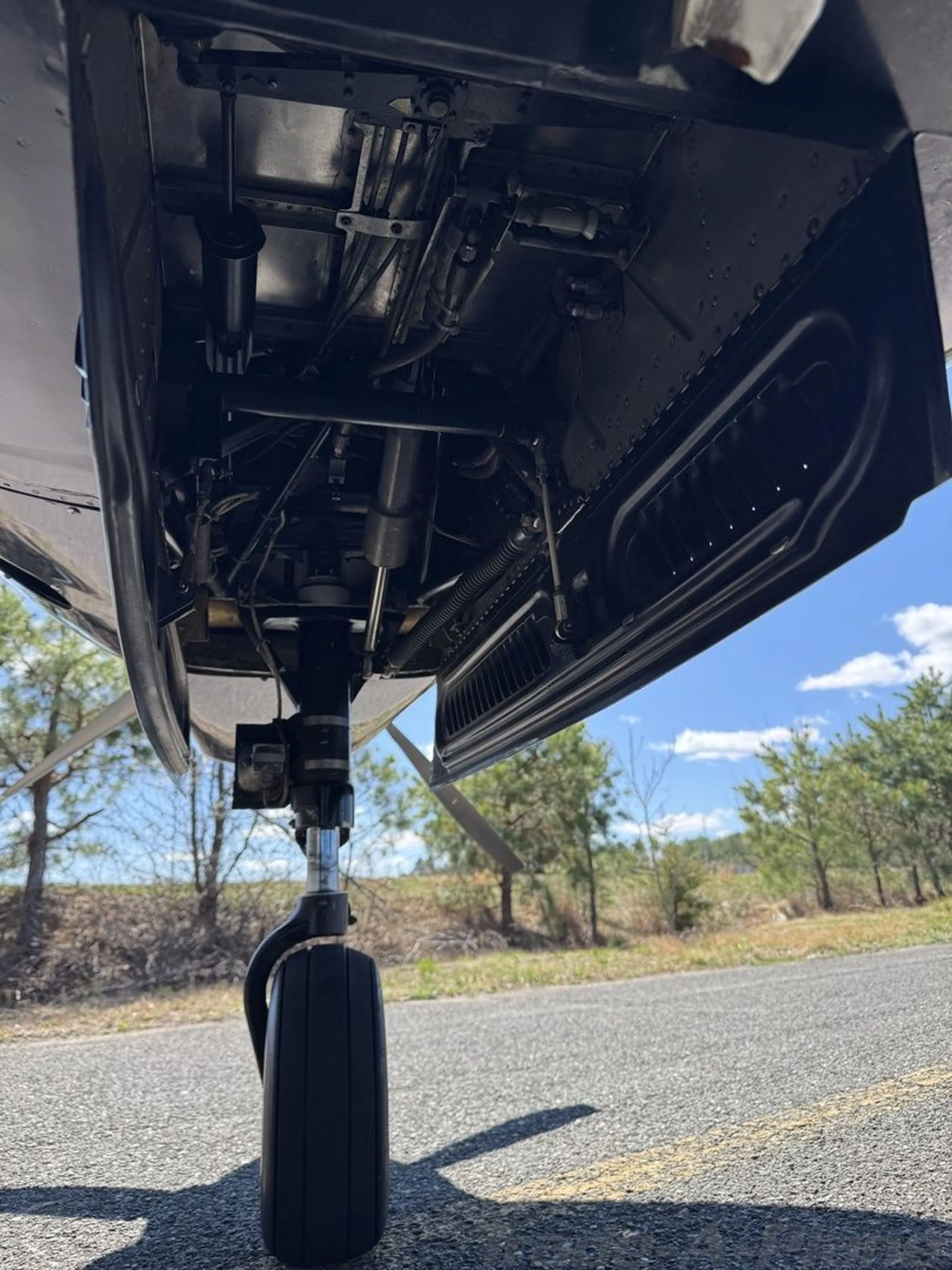 A low-angle view showing the exposed landing gear mechanism and wheel of the aircraft.