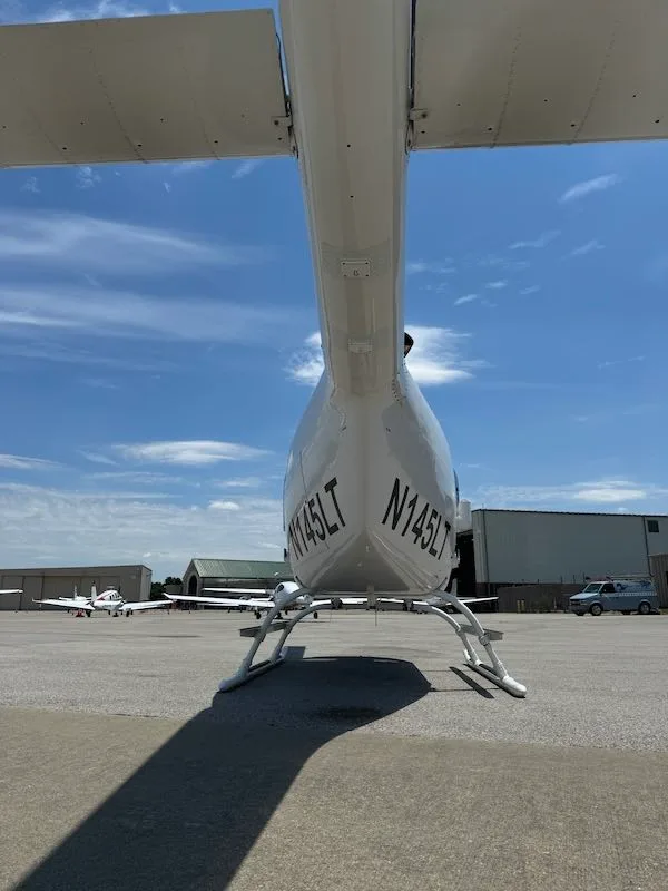 Rear view of a white Bell 206L-4 helicopter with tail number N145LT on the tarmac.