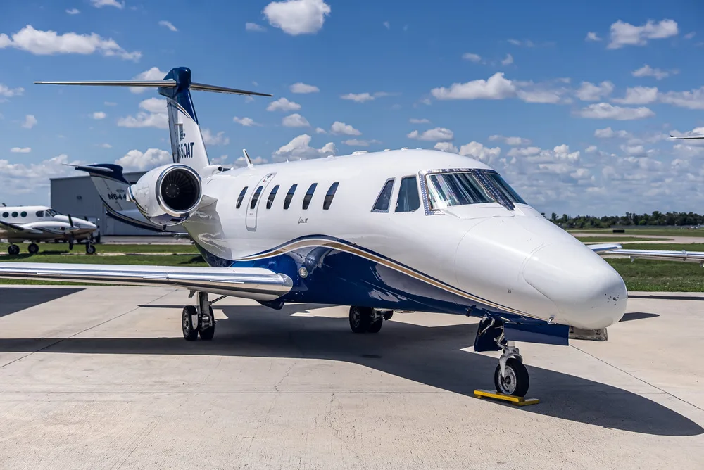 A front-left view of the white and blue Cessna Citation III business jet, N650AT, parked on an airfield under a blue sky.