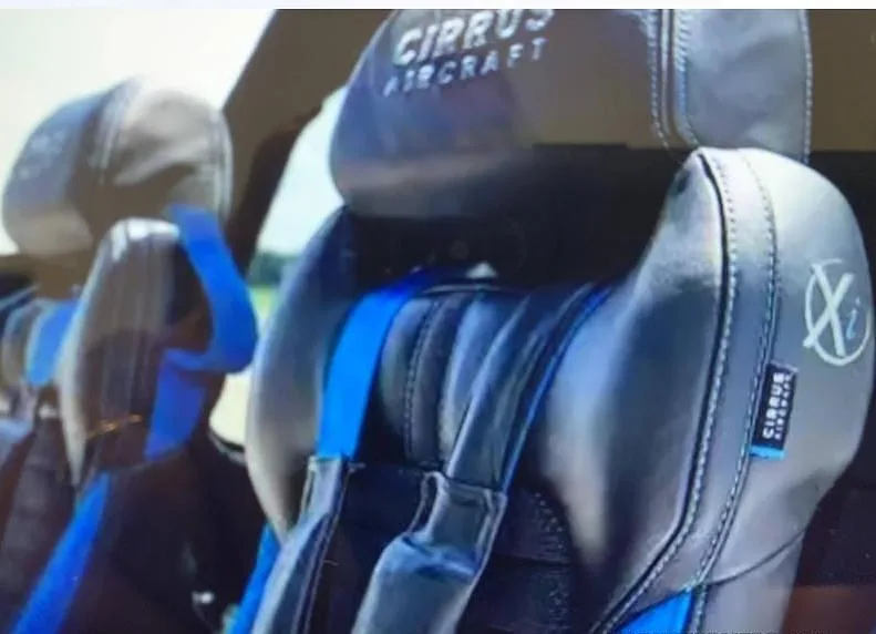 Close-up of the black and blue leather interior seats of a Cirrus aircraft, with "CIRRUS AIRCRAFT" logo on the headrest.