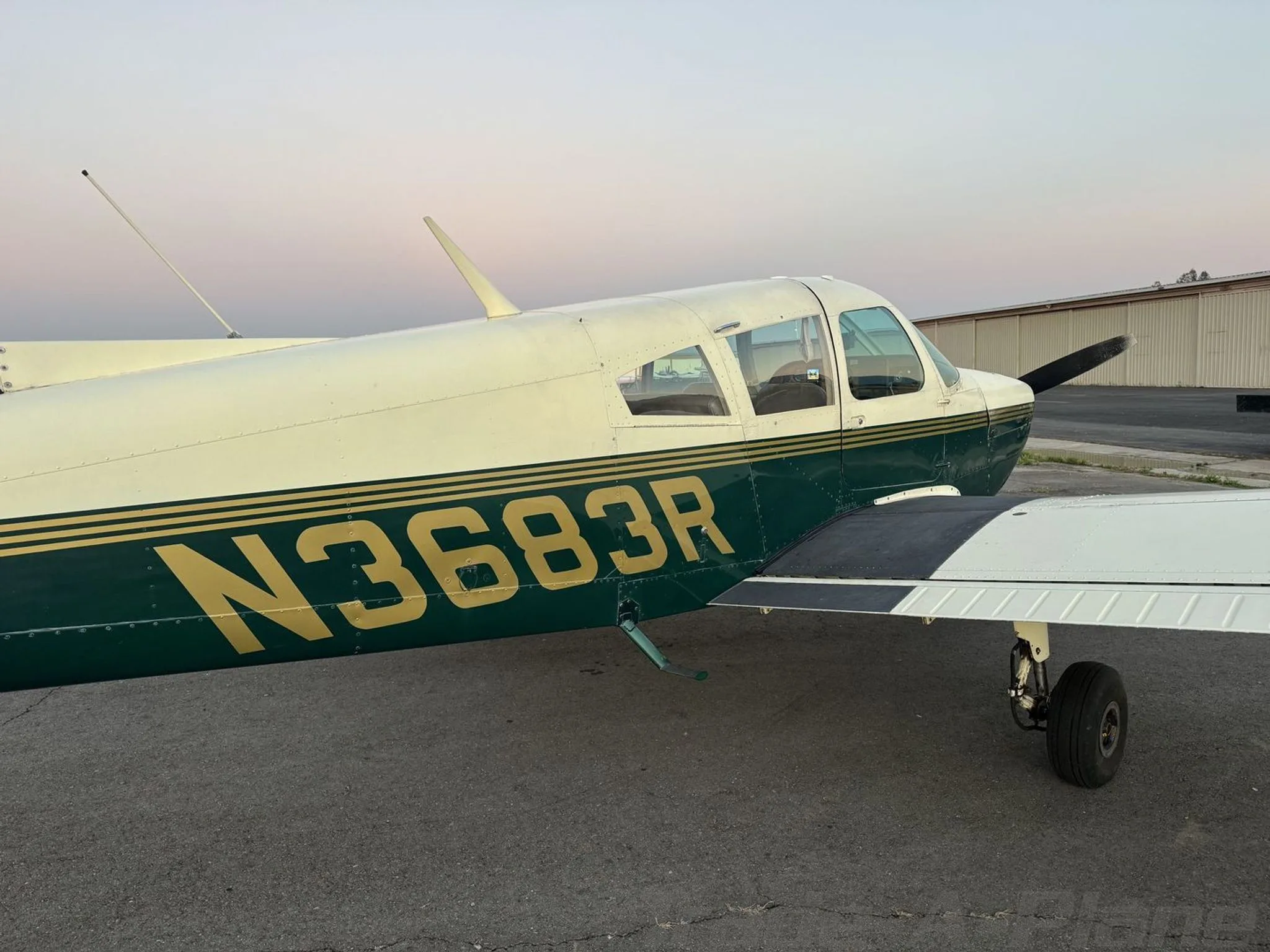 A close-up side view of the N3683R aircraft's fuselage and wing, showing its green and white paint scheme.