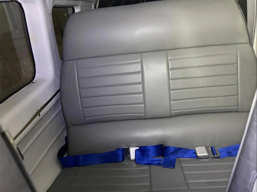 A view of the grey rear passenger seats with blue seatbelts inside the aircraft cabin.
