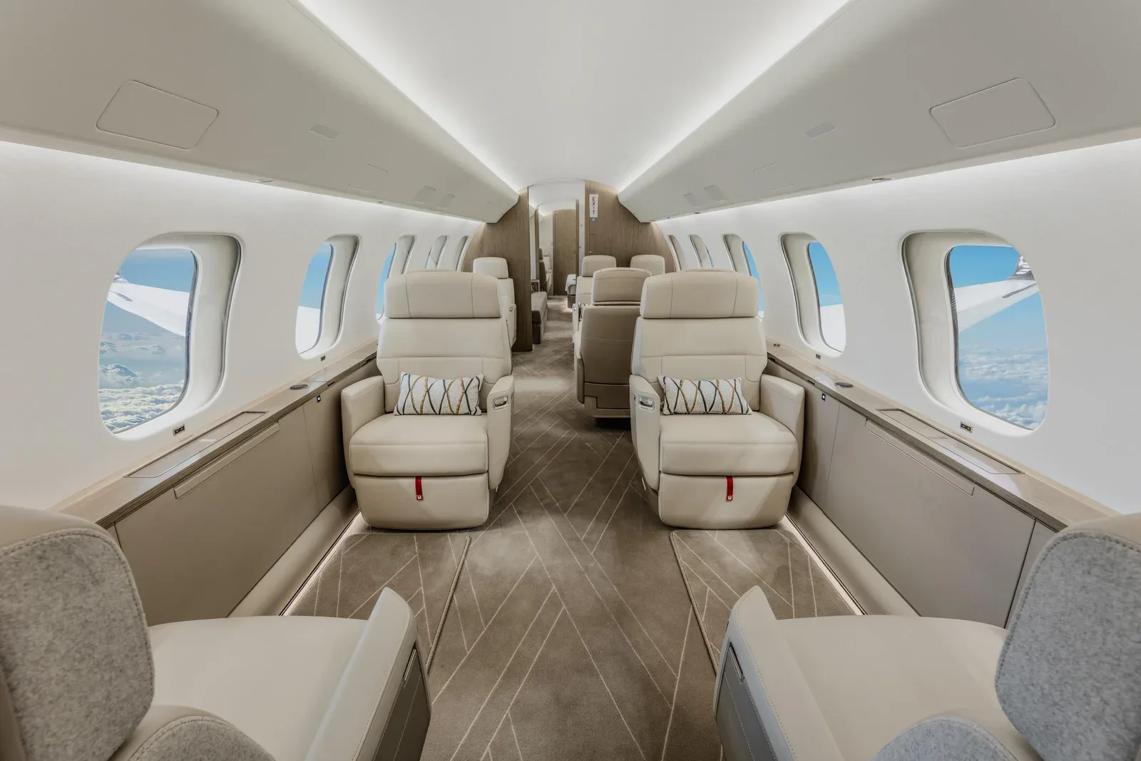 The luxurious cabin interior of a business jet with light-colored leather seats and patterned carpet.