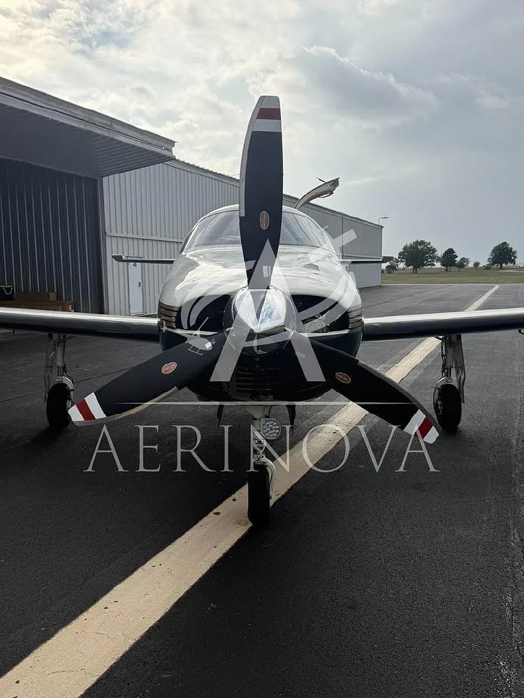 A head-on view of the Piper Malibu Mirage N92821 with its propeller, parked on an airfield.
