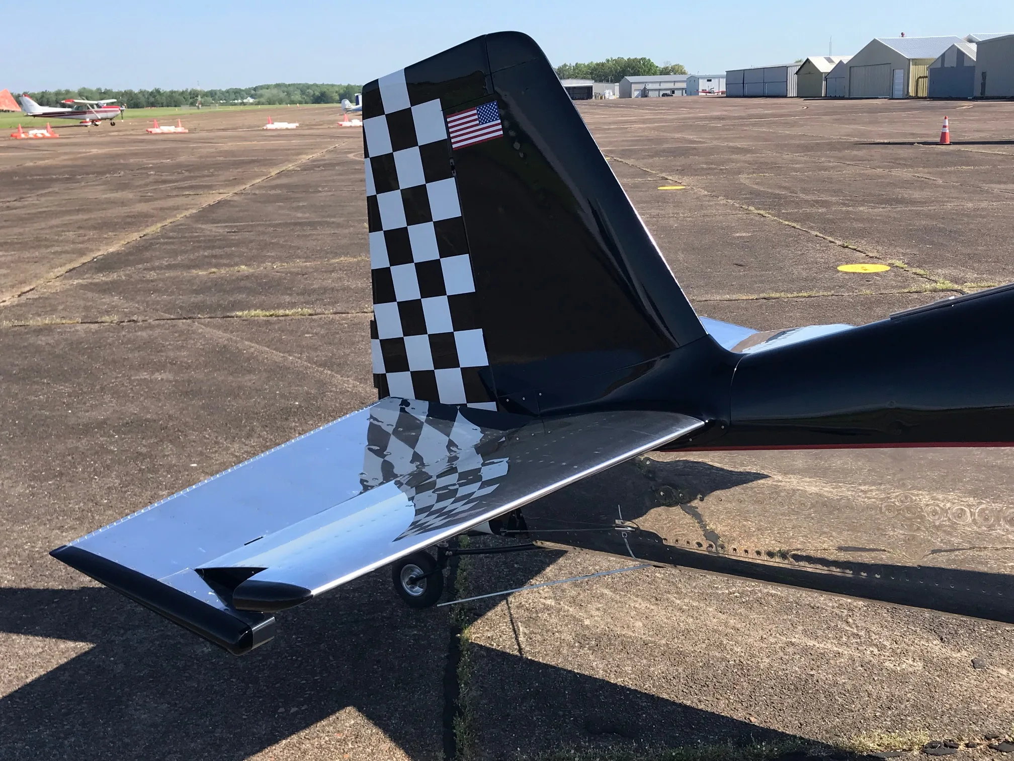 A close-up of the experimental aircraft's tail, featuring a black and white checkered pattern and an American flag decal.