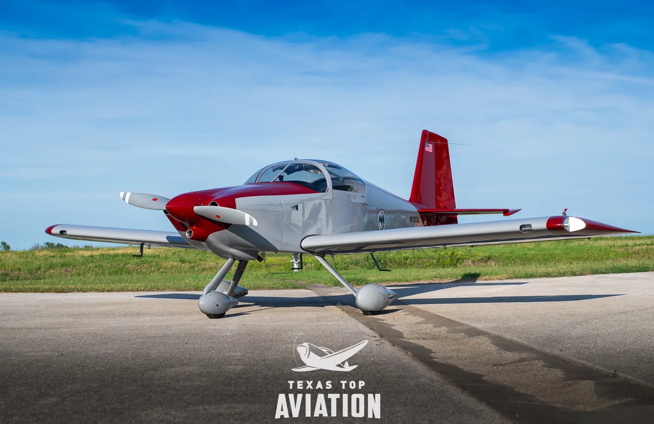 A gray and red single-engine aircraft, N1359L, with its tail number visible, parked on a tarmac.