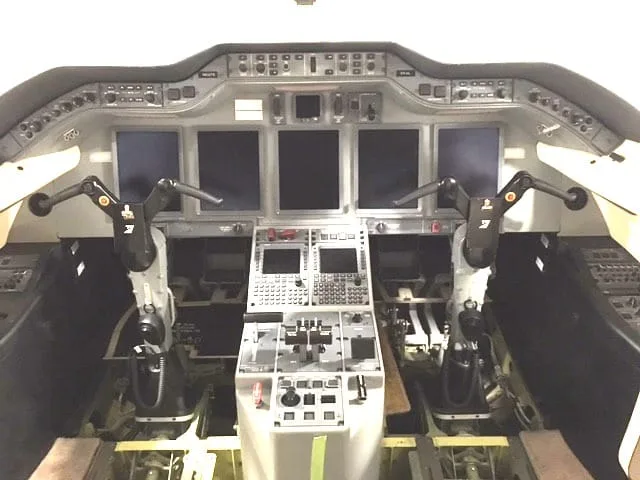 The modern cockpit of a business jet features multiple digital displays and control yokes.