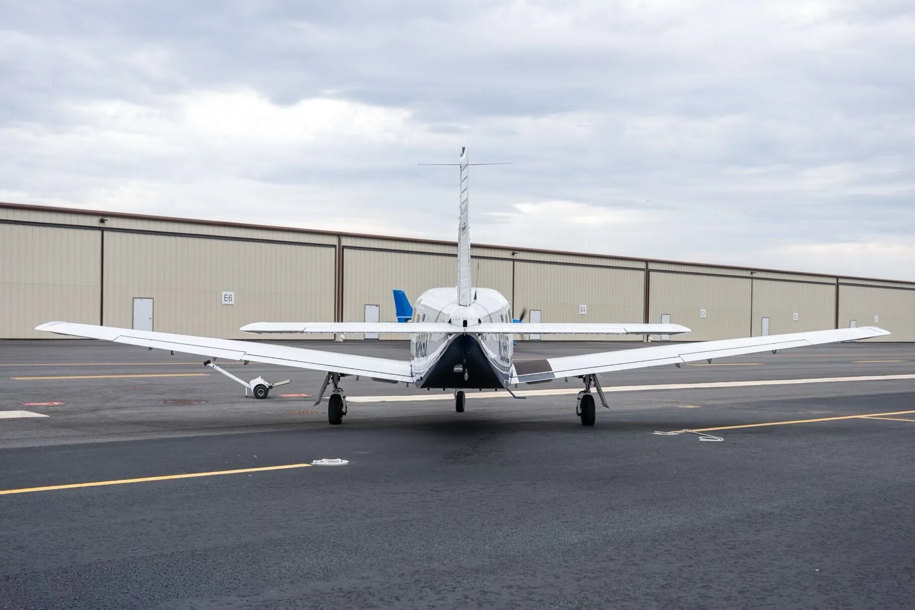 A rear view of a white Piper Saratoga II TC aircraft, tail number N269Z, parked on the tarmac in front of hangars.
