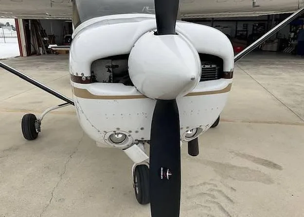 A close-up front view of the white Cessna aircraft's propeller and engine cowling.