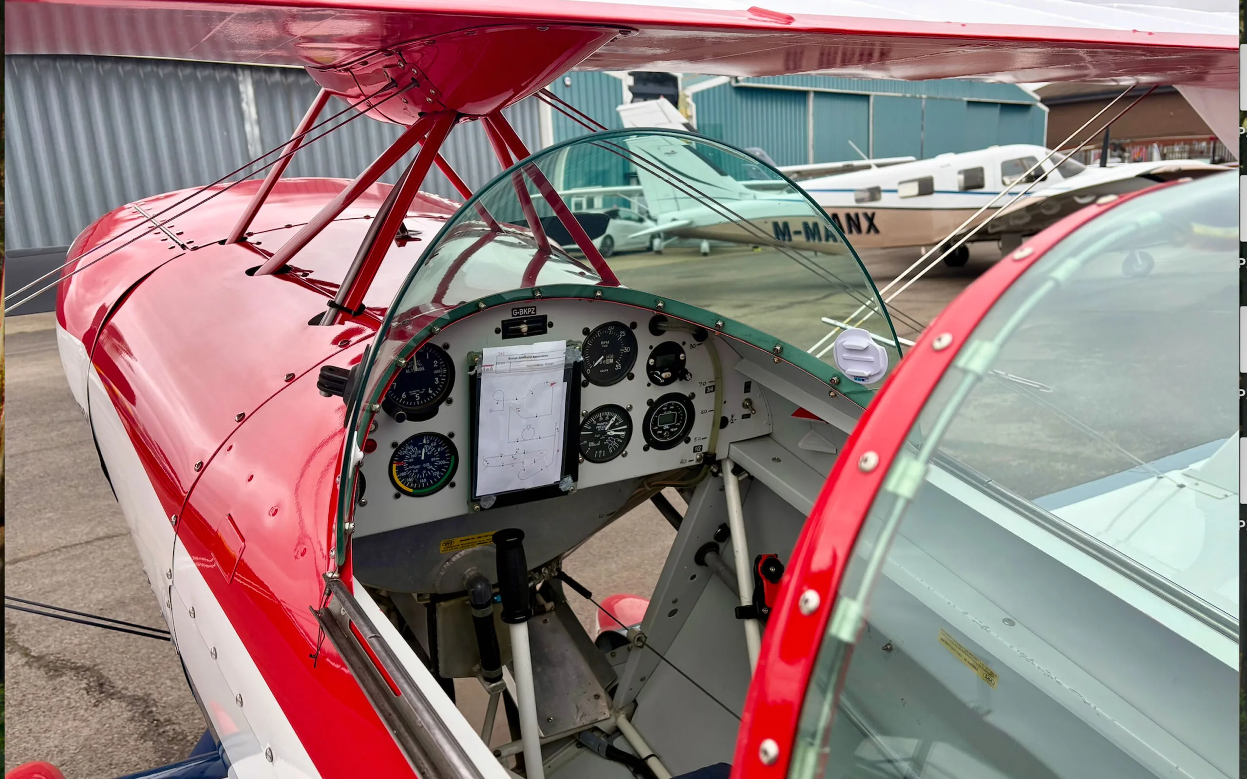 A view into the cockpit of a red and white Pitts S1T biplane, showing the instrument panel.