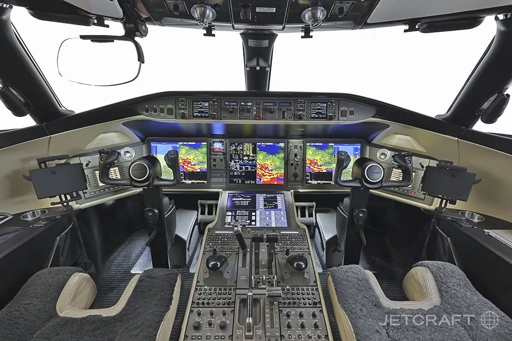 The cockpit of a Bombardier Global 6000, showing the instrument panel with multiple large digital displays and control yokes.