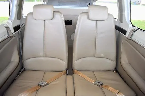 Two light-colored leather aircraft seats in the cabin, viewed from the front.